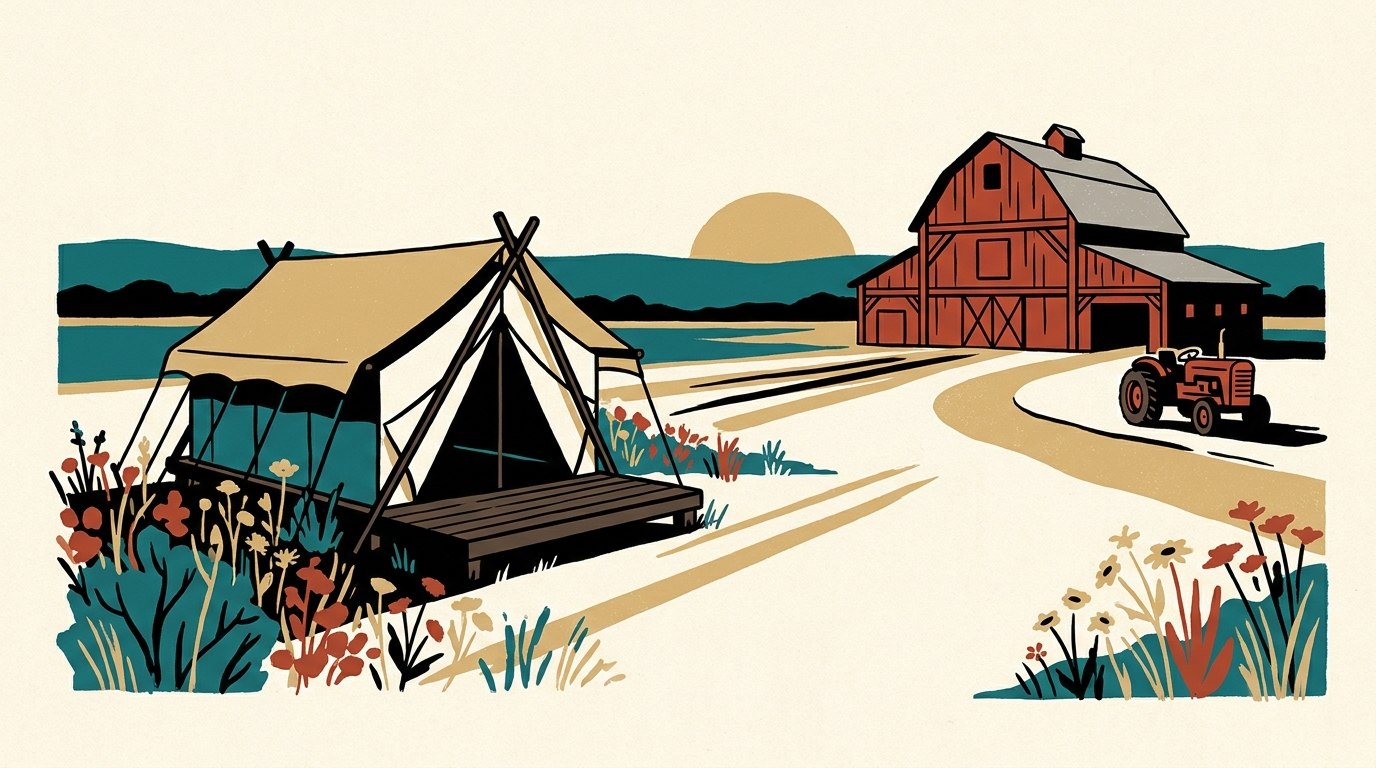 A canvas safari tent on a wooden platform sits in a field of wildflowers near a historic red barn under a golden late afternoon sky.